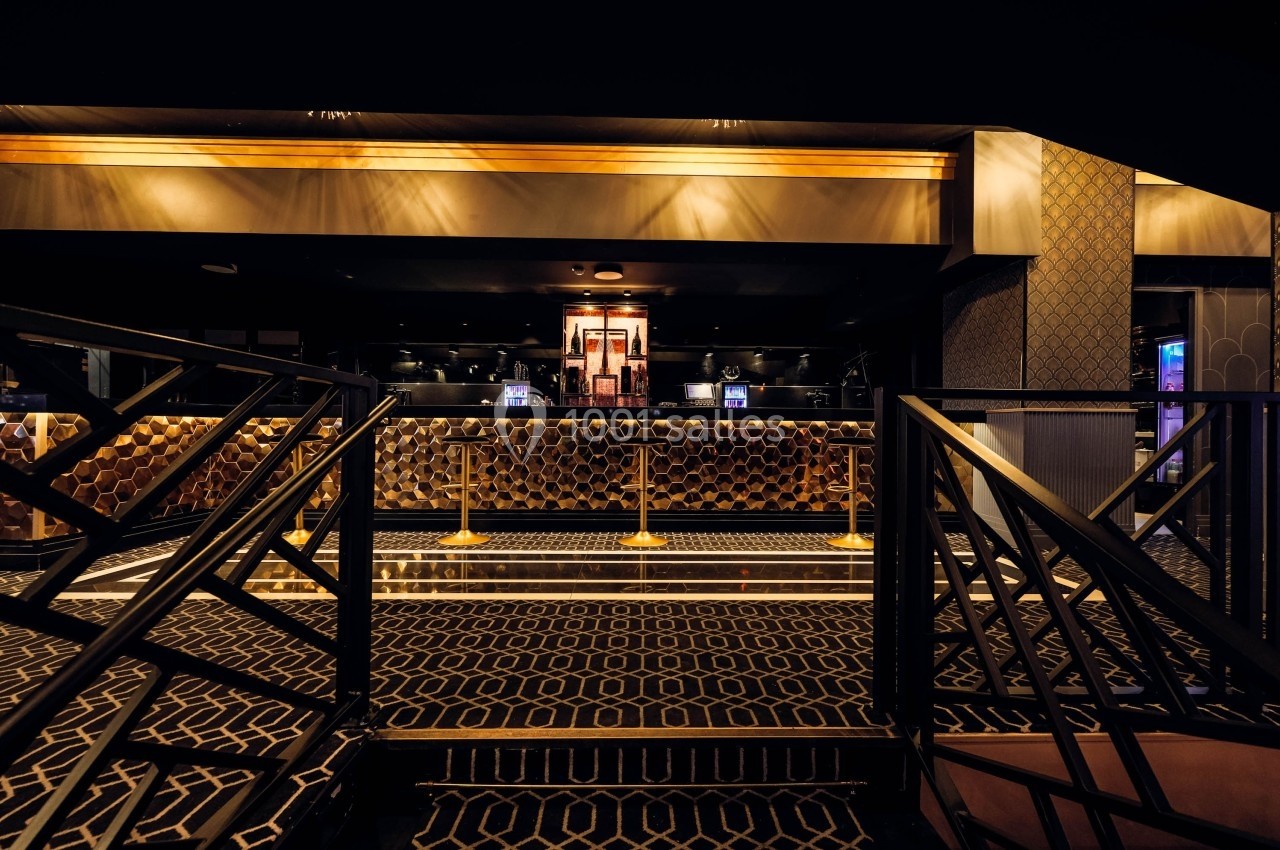 Intérieur d'un hall élégant avec comptoir en arrière-plan, décor doré et motifs géométriques au sol.