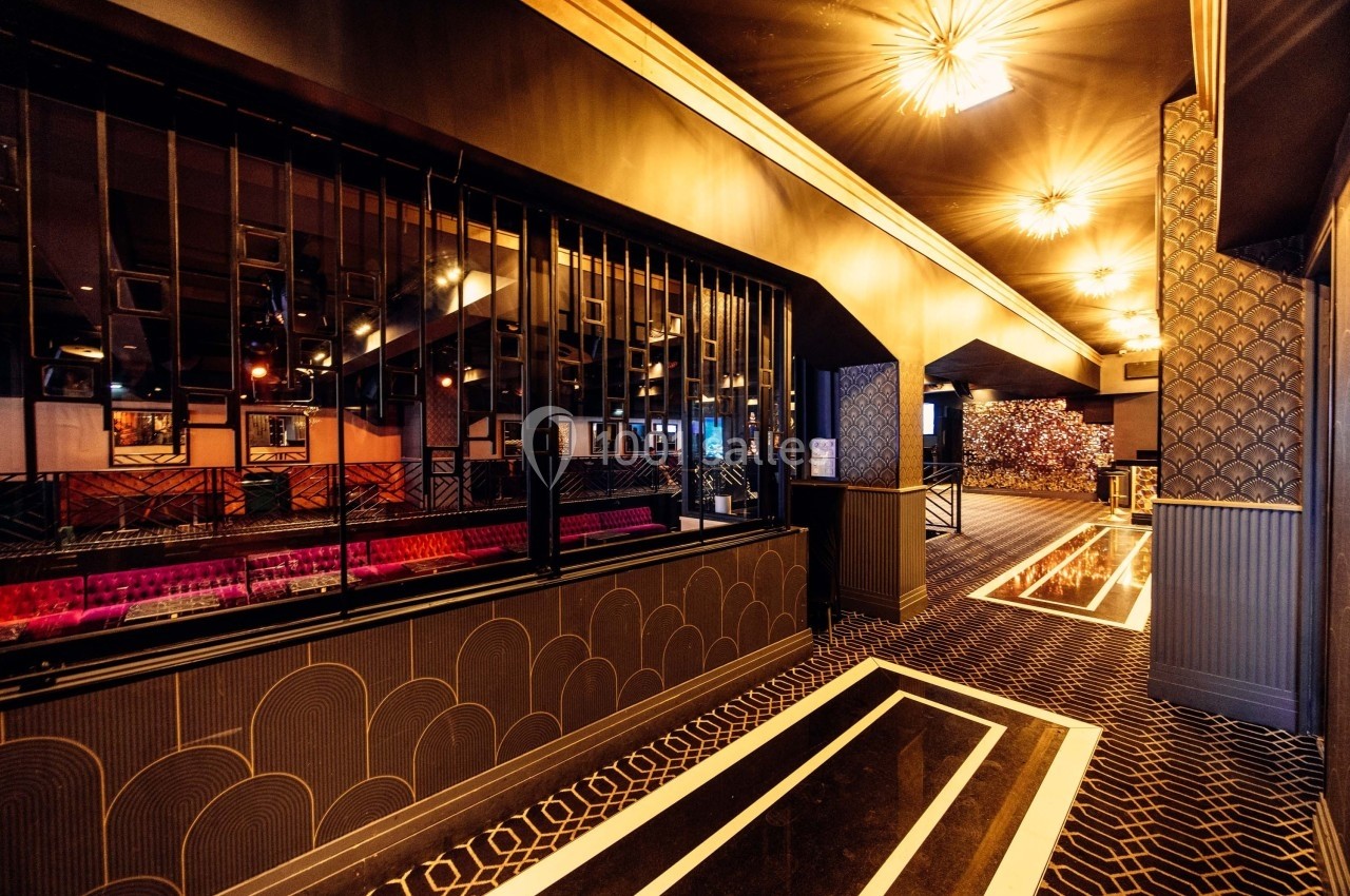 Intérieur d'une salle élégante avec des motifs géométriques, des lumières suspendues et des sièges visibles à travers une…