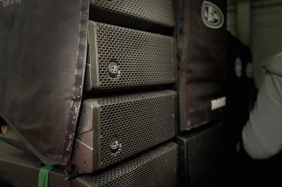 Enceintes de sonorisation empilées dans une configuration de type line array, partiellement couvertes par des housses.