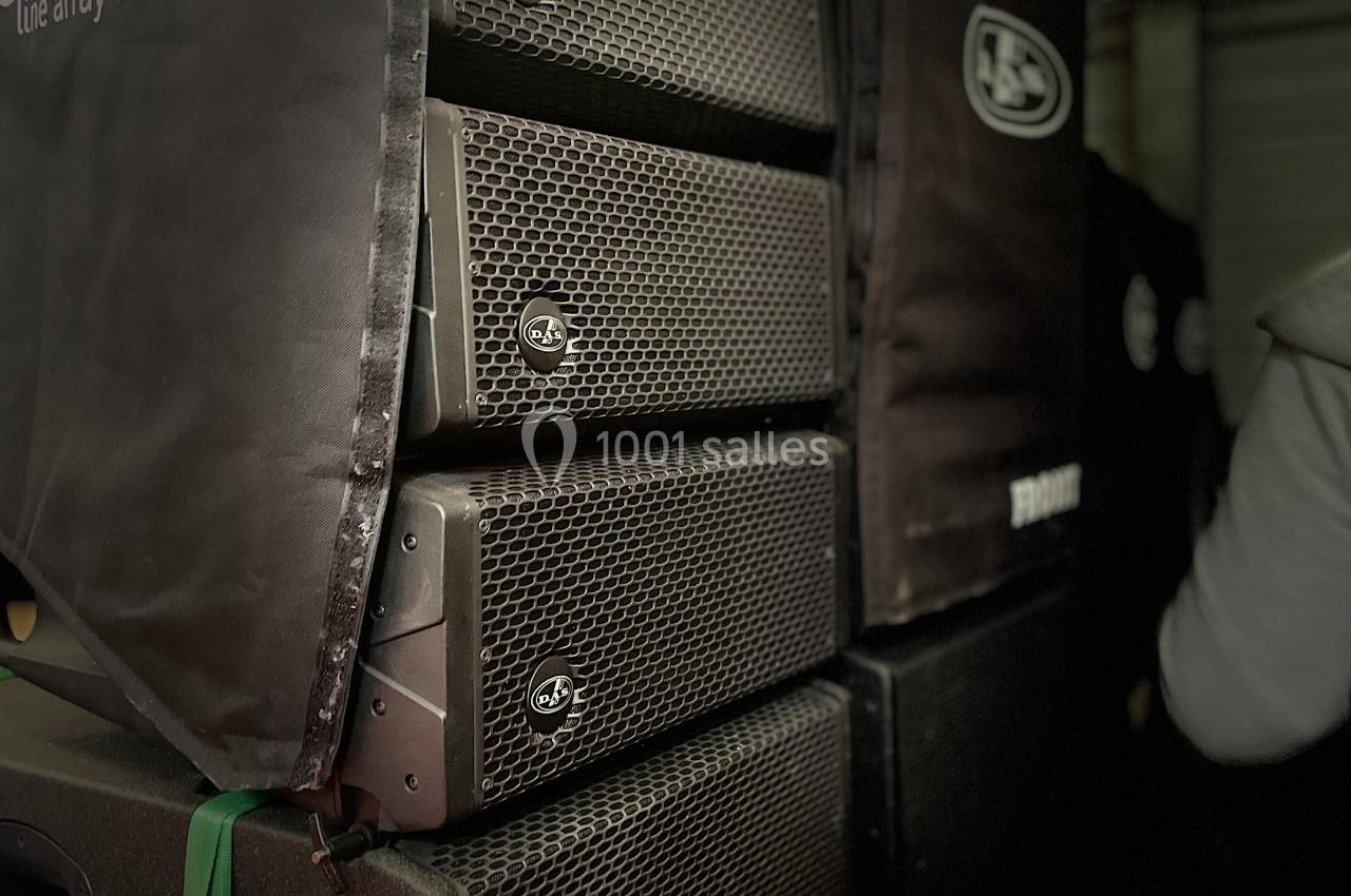 Enceintes de sonorisation empilées dans une configuration de type line array, partiellement couvertes par des housses.