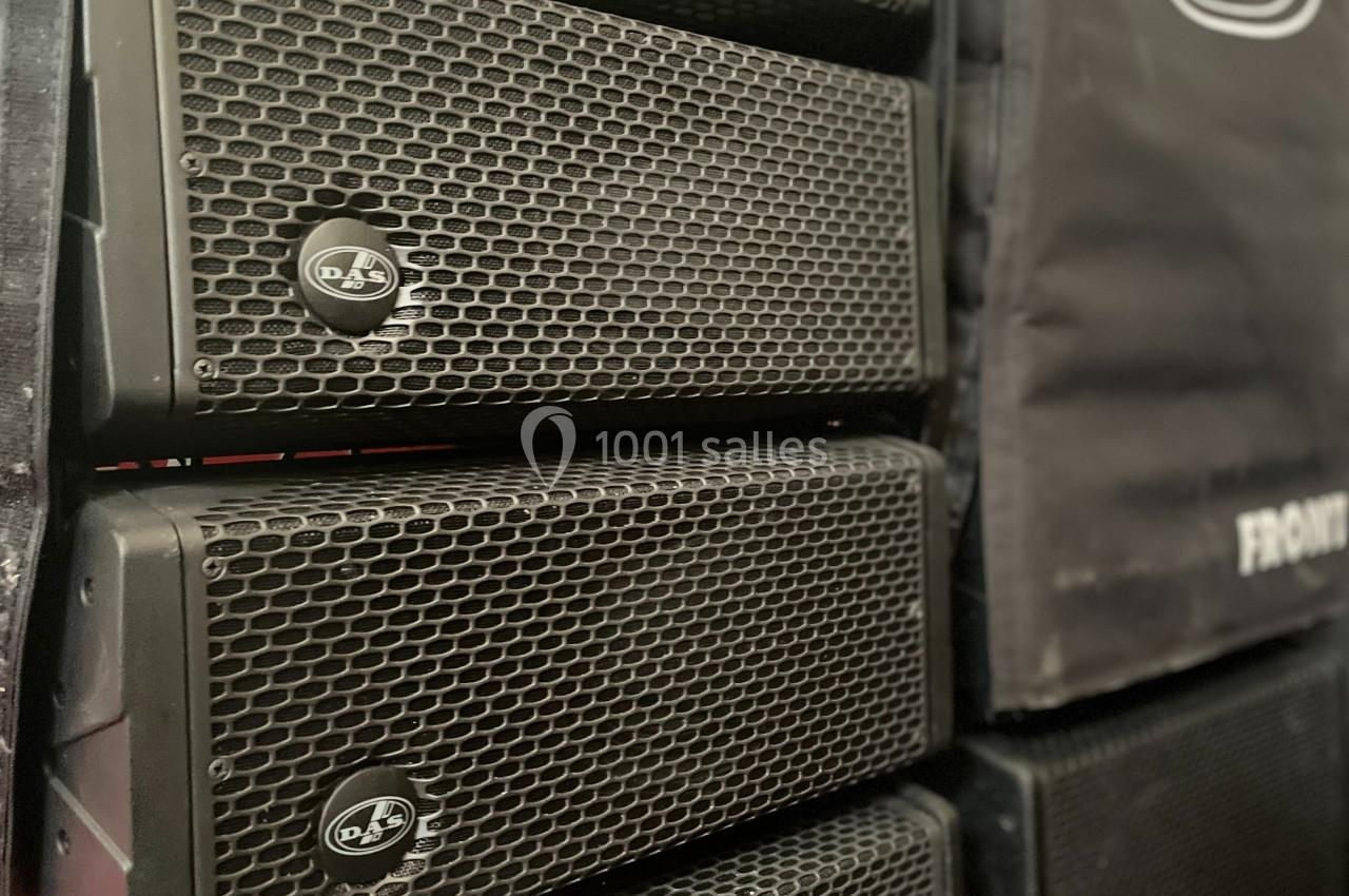 Enceintes de sonorisation empilées avec des grilles métalliques noires et une housse de protection partiellement visible.