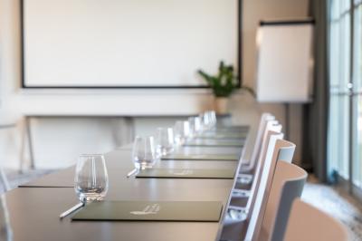 Lit avec tête de lit en velours, table d'appoint ronde et fenêtre avec rideaux dans une chambre lumineuse.