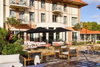 Lit avec tête de lit en velours, table d'appoint ronde et fenêtre avec rideaux dans une chambre lumineuse.