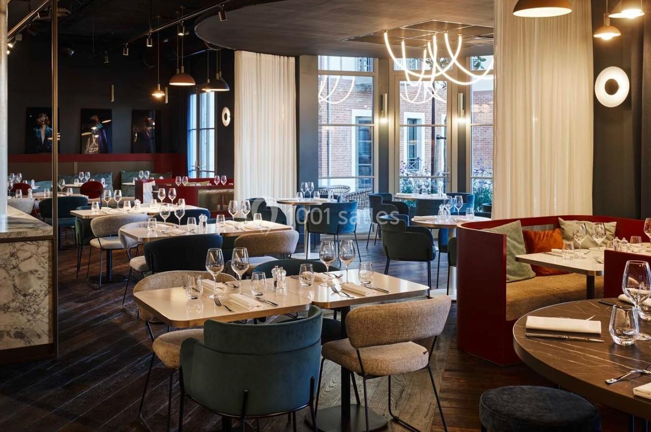 Salle de restaurant élégante avec tables dressées, chaises modernes, éclairage design et grandes fenêtres donnant sur l…