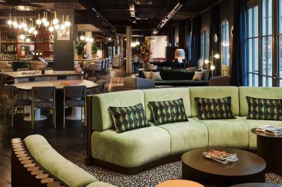 Lit avec tête de lit en velours, table d'appoint ronde et fenêtre avec rideaux dans une chambre lumineuse.