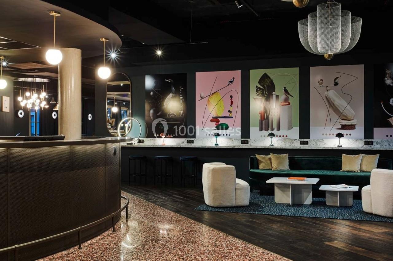 Intérieur d'un espace moderne avec comptoir arrondi, fauteuils, tables basses et décorations murales colorées.