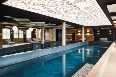 Lit avec tête de lit en velours, table d'appoint ronde et fenêtre avec rideaux dans une chambre lumineuse.