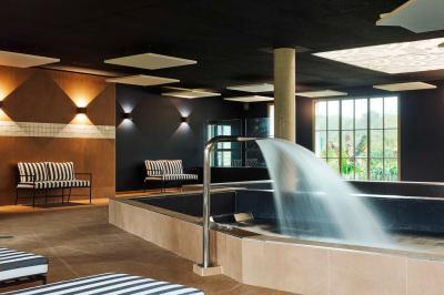 Lit avec tête de lit en velours, table d'appoint ronde et fenêtre avec rideaux dans une chambre lumineuse.