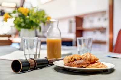 Bateau amarré sur un quai, avec vue sur une rivière, des bâtiments historiques et un pont en arrière-plan.