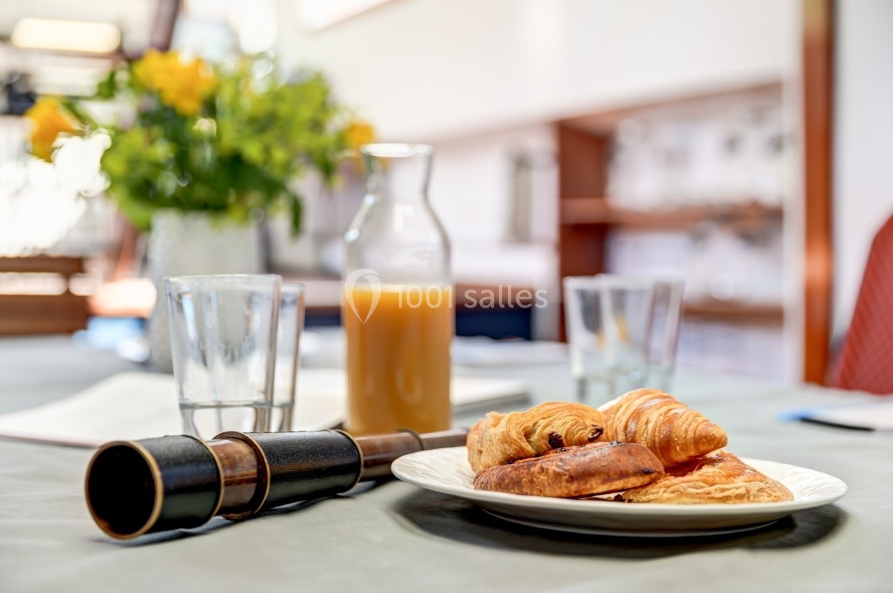 Assiette de viennoiseries avec croissant, pain au chocolat et jus d'orange sur une table dressée.