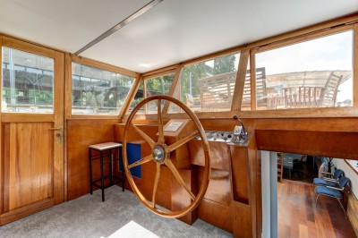 Bateau amarré sur un quai, avec vue sur une rivière, des bâtiments historiques et un pont en arrière-plan.