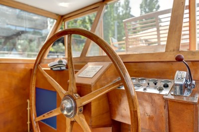 Bateau amarré sur un quai, avec vue sur une rivière, des bâtiments historiques et un pont en arrière-plan.