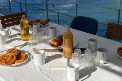 Bateau amarré sur un quai, avec vue sur une rivière, des bâtiments historiques et un pont en arrière-plan.