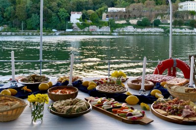 Bateau amarré sur un quai, avec vue sur une rivière, des bâtiments historiques et un pont en arrière-plan.