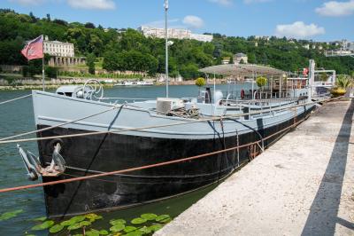 Poste de pilotage en bois d'un bateau avec un grand volant, des commandes et des fenêtres laissant entrer la lumière.