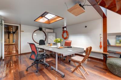 Poste de pilotage en bois d'un bateau avec un grand volant, des commandes et des fenêtres laissant entrer la lumière.