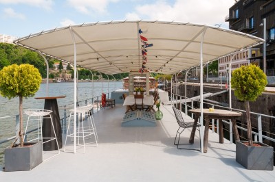 Bateau amarré sur une rivière avec des bâtiments historiques et une colline en arrière-plan.