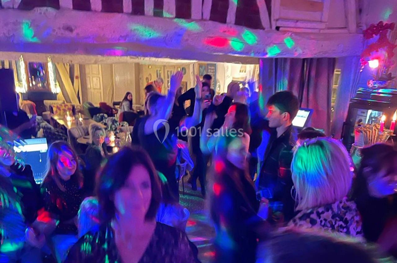 Groupe de personnes dans une ambiance festive avec éclairages colorés dans une salle à la décoration rustique.