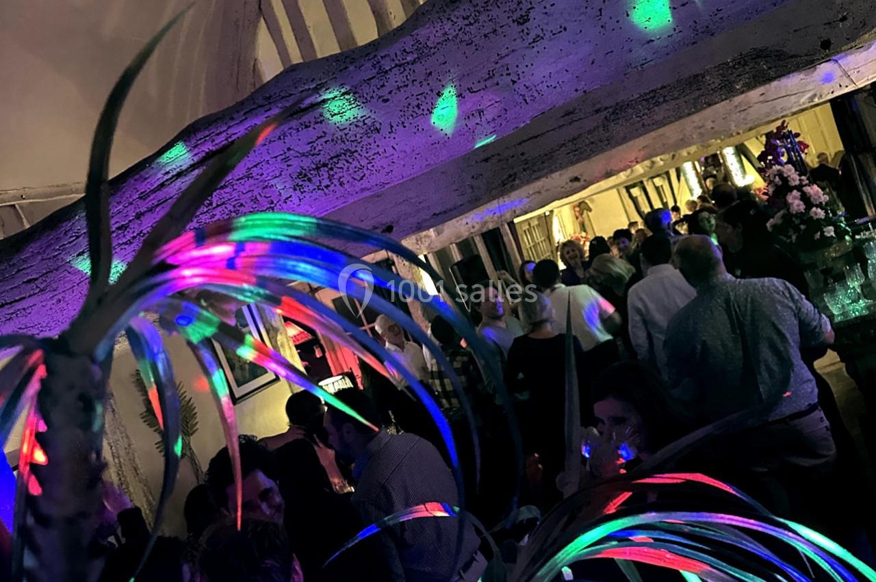 Groupe de personnes lors d'une soirée festive avec des lumières colorées et une décoration végétale au premier plan.