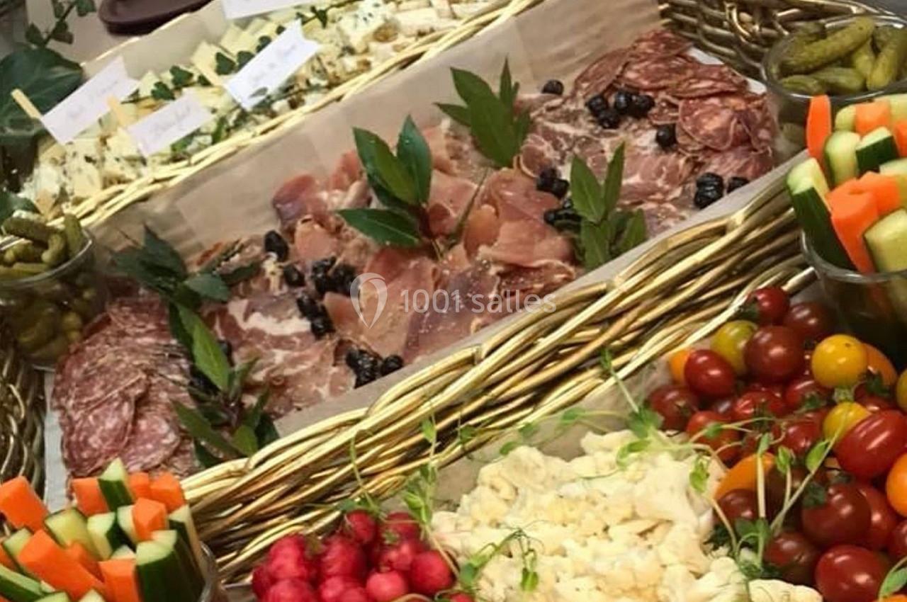 Plateau garni de charcuteries, fromages, légumes croquants, tomates cerises et cornichons, présenté dans un panier en osier.