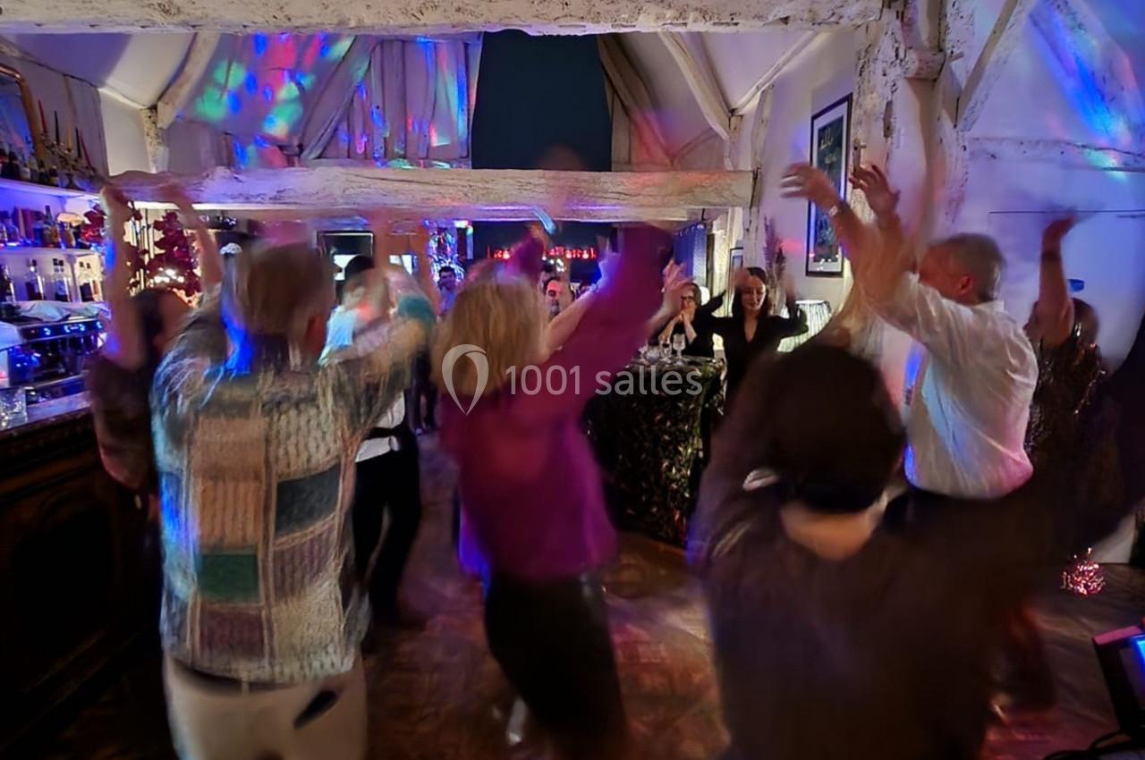 Personnes dansant dans une salle éclairée par des lumières colorées, ambiance festive et conviviale.