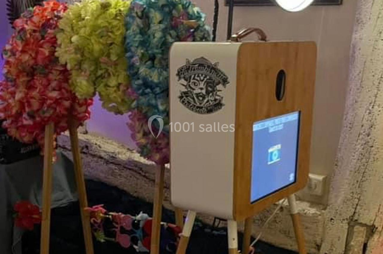 Borne photo en bois avec écran tactile, entourée de guirlandes hawaïennes colorées et éclairée par un anneau lumineux.