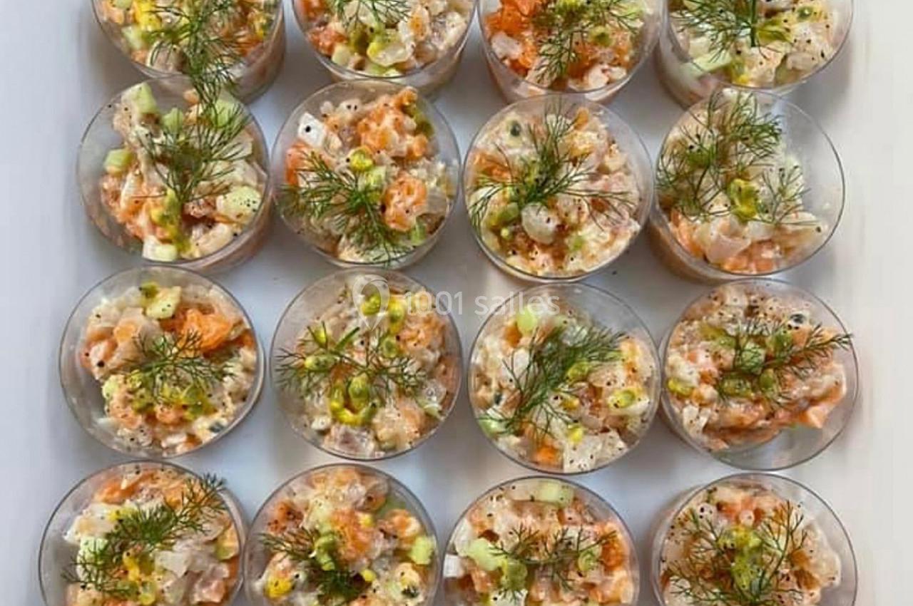 Verrines de tartare de poisson et légumes, garnies d'aneth, disposées en rangées sur une surface blanche.