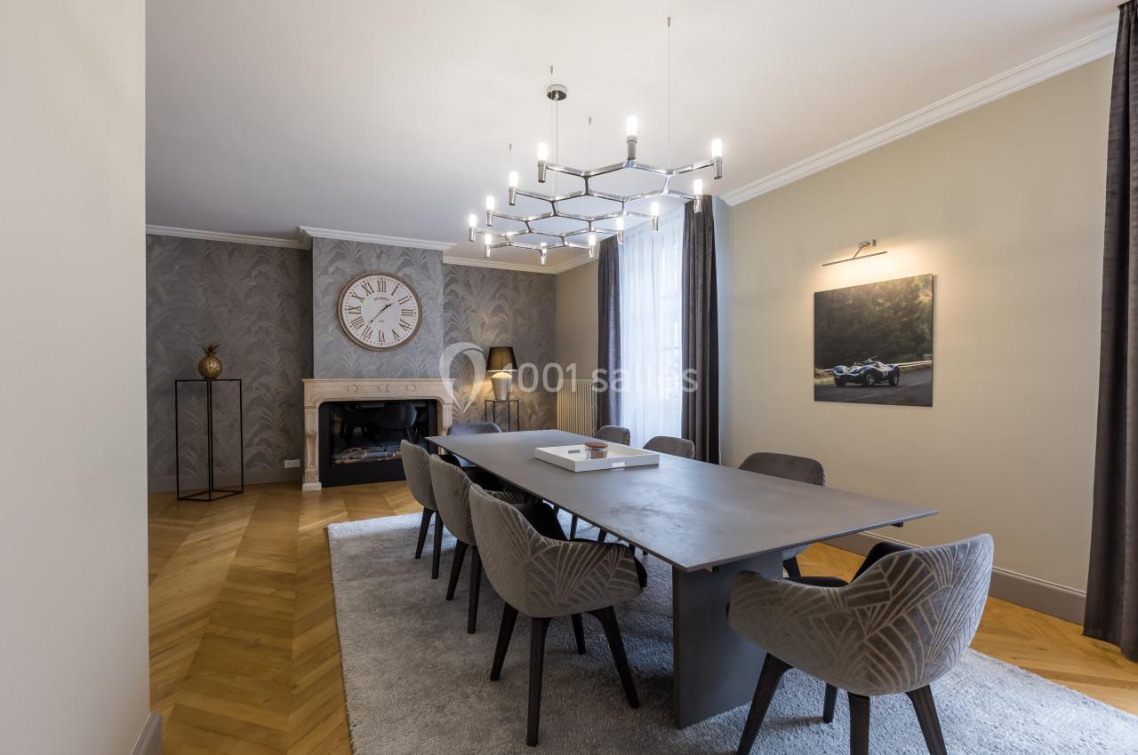 Salle à manger élégante avec une grande table, des chaises modernes, un lustre design et une cheminée décorative.