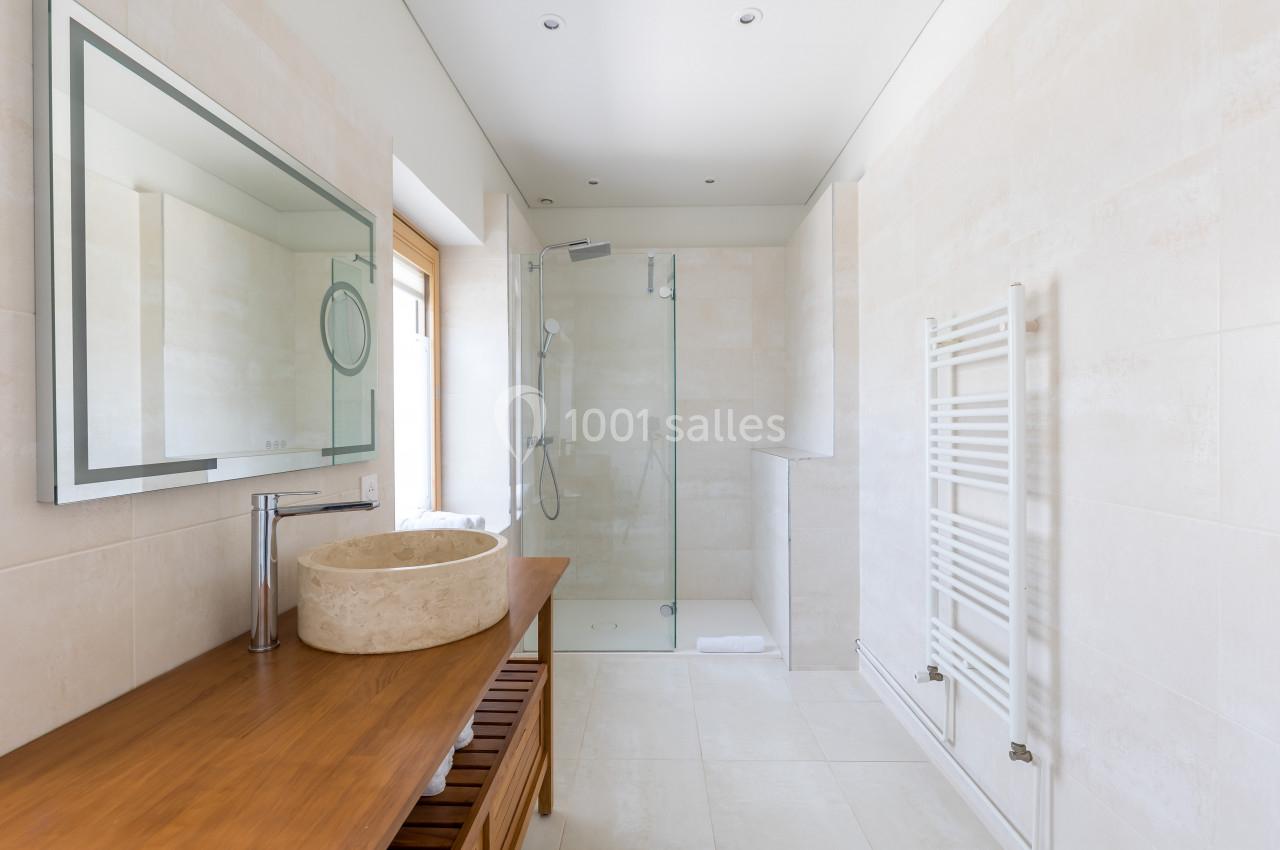 Salle de bain moderne avec douche vitrée, vasque en pierre sur meuble en bois et sèche-serviettes mural.