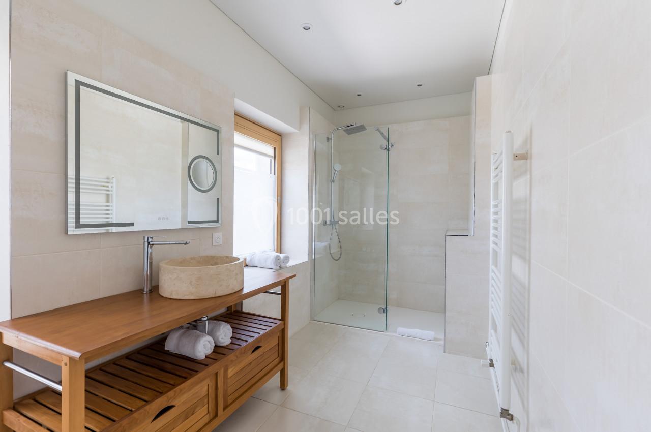 Salle de bain moderne avec douche à l'italienne, meuble en bois avec vasque et grand miroir rectangulaire.