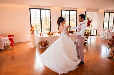 Entrée d'un bâtiment moderne entourée de cyprès et d'oliviers, avec un chemin menant à une porte vitrée.