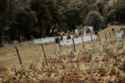 Chaises blanches disposées en extérieur dans un vignoble, avec quelques personnes en train de préparer l'espace.