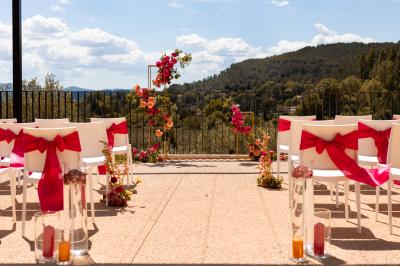 Entrée d'un bâtiment moderne entourée de cyprès et d'oliviers, avec un chemin menant à une porte vitrée.