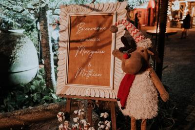 Costume de mariage bleu foncé avec chemise blanche et nœud papillon floral, suspendu sur un cintre gravé.