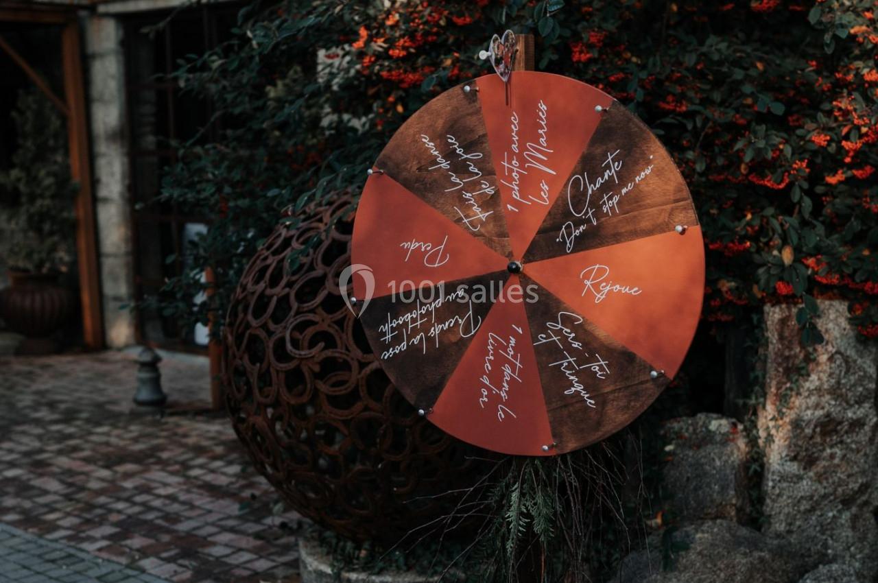 Roue en bois rouge avec des inscriptions manuscrites, installée dans un jardin avec des plantes et des pavés.