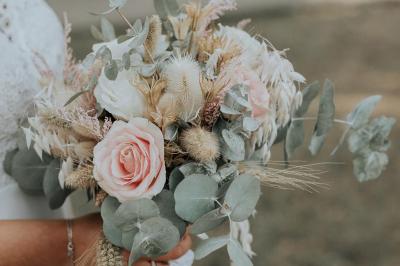 Costume de mariage bleu foncé avec chemise blanche et nœud papillon floral, suspendu sur un cintre gravé.
