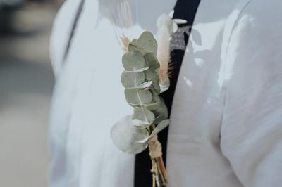 Costume de mariage bleu foncé avec chemise blanche et nœud papillon floral, suspendu sur un cintre gravé.