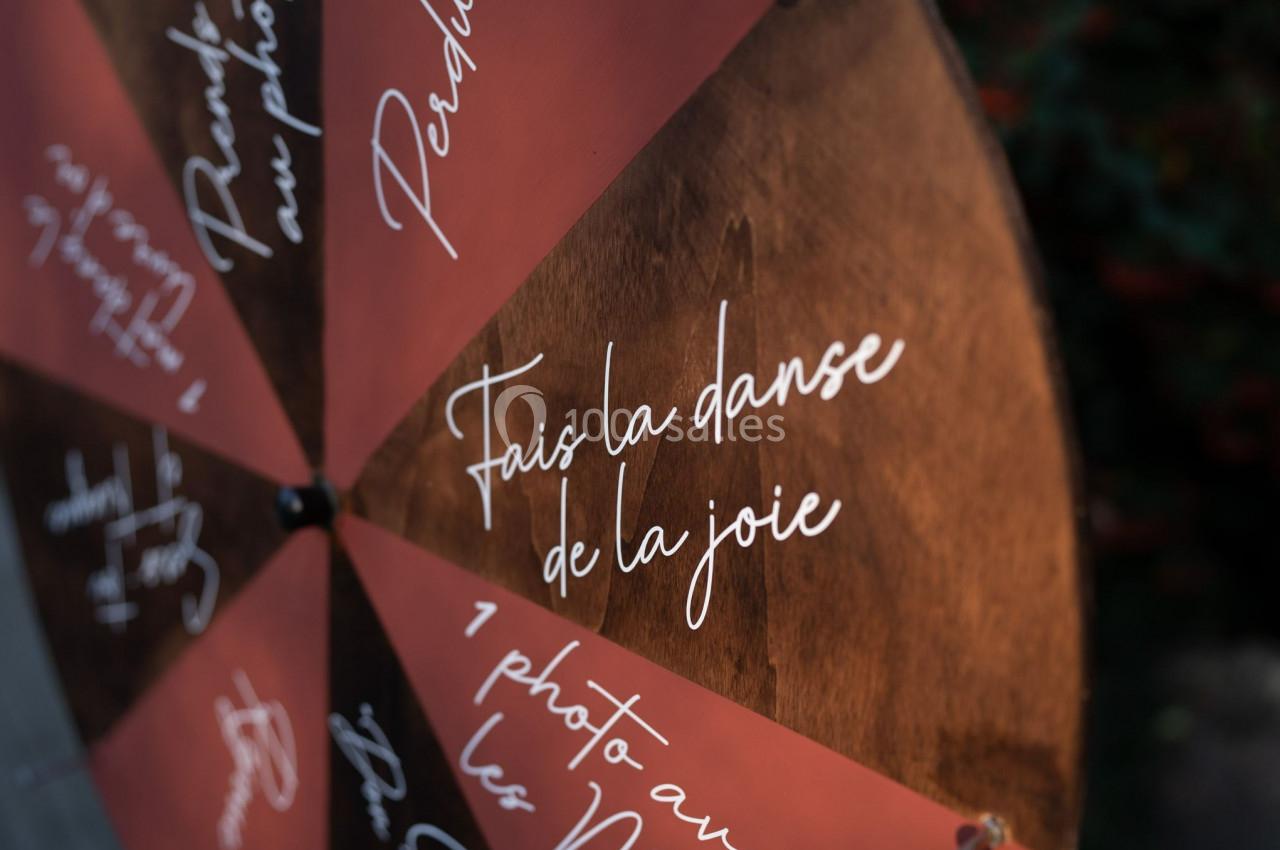 Roulette en bois avec des segments colorés portant des inscriptions manuscrites, dont ’Fais la danse de la joie’.