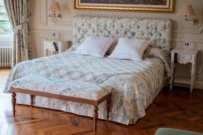 Costume de mariage bleu foncé avec chemise blanche et nœud papillon floral, suspendu sur un cintre gravé.