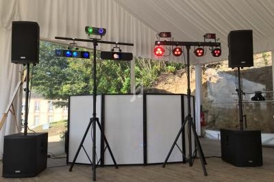 Installation de matériel de sonorisation et d'éclairage sous une tente, avec haut-parleurs et projecteurs colorés.