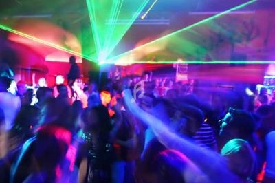 Foule dans une boîte de nuit avec des lumières colorées et des faisceaux laser illuminant la piste de danse.