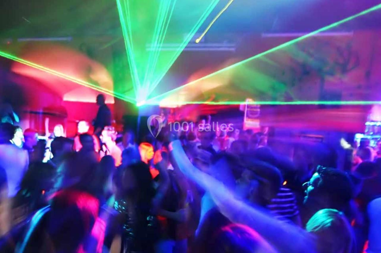 Foule dans une discothèque avec des lumières colorées et des faisceaux laser illuminant la salle.