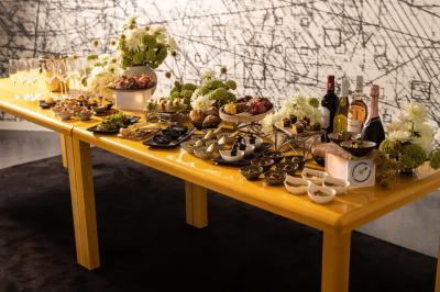 Assortiment de viennoiseries et fruits frais disposés sur un comptoir en métal dans un espace lumineux.