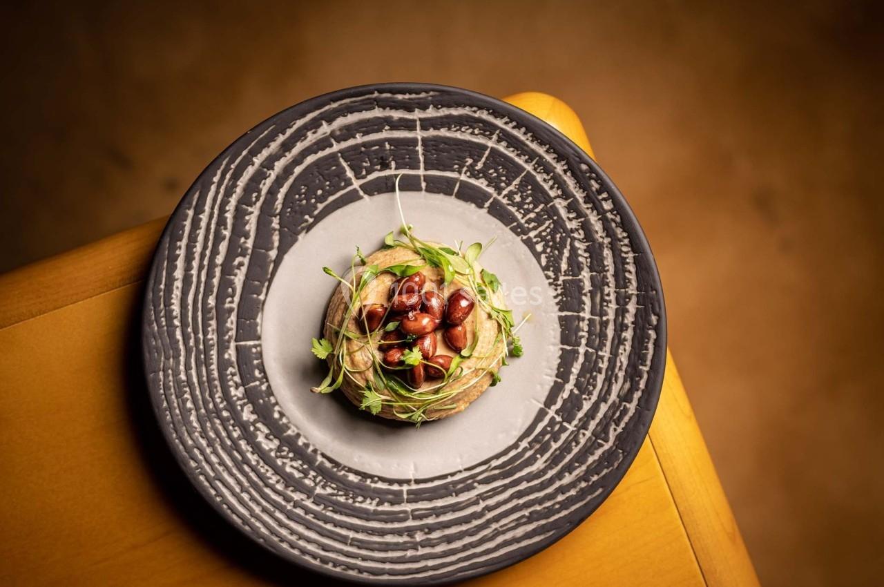 Assiette garnie d'une préparation végétale avec haricots rouges et pousses vertes, présentée sur une table en bois.