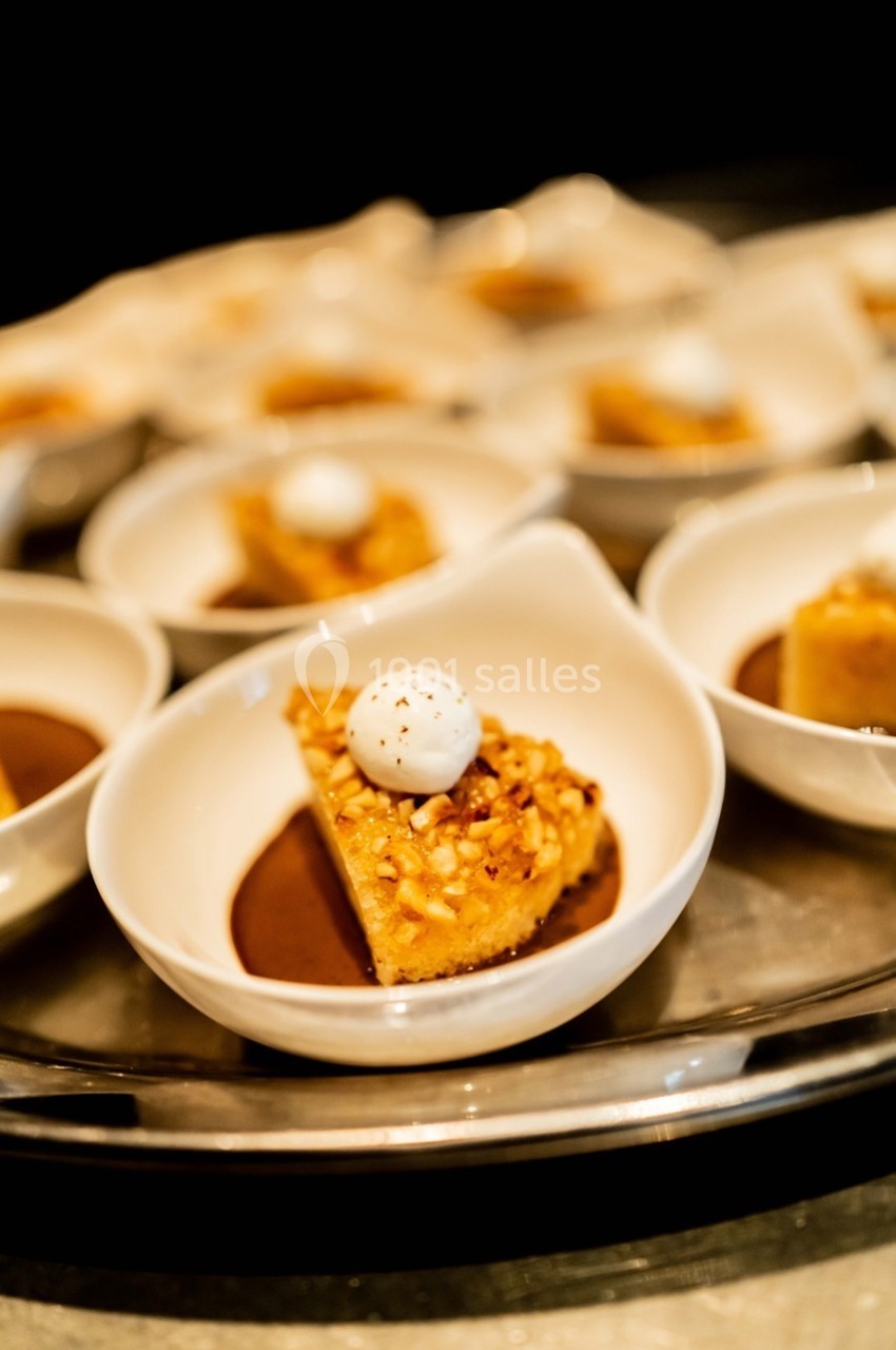 Part de dessert aux noix avec une boule de crème sur le dessus, servie dans une petite coupelle blanche.