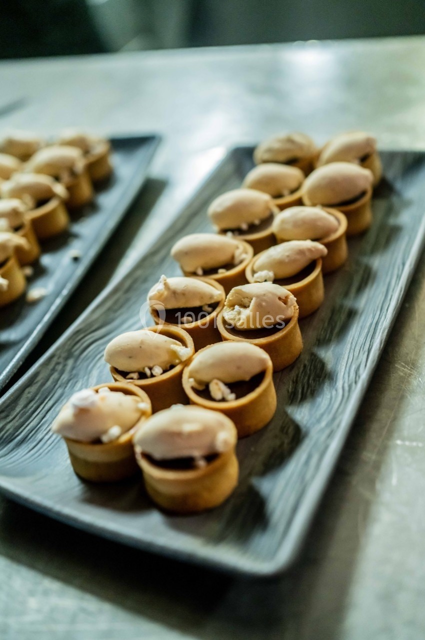 Petits desserts individuels dans des tartelettes garnies de crème et de morceaux de noix, disposés sur des plateaux.