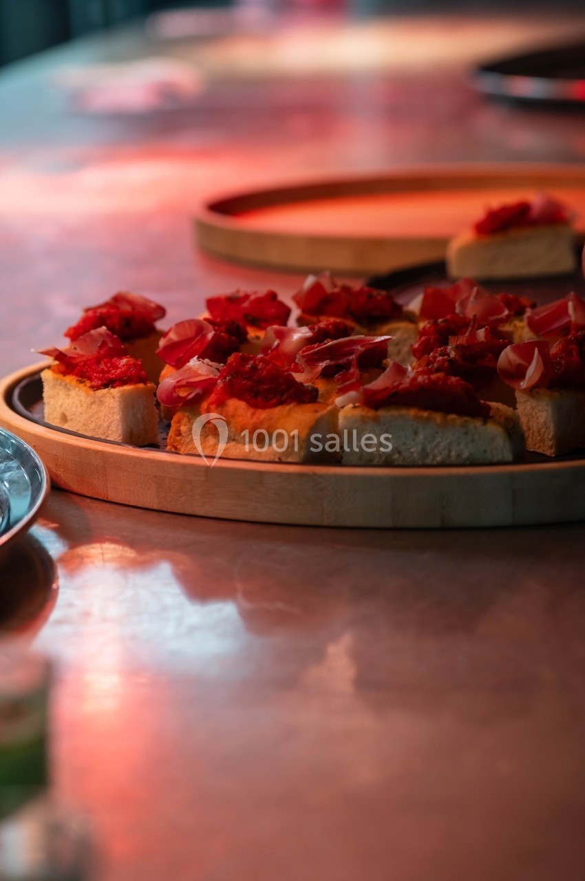 Tranches de pain garnies de tomates, oignons et condiments, présentées sur un plateau en bois.