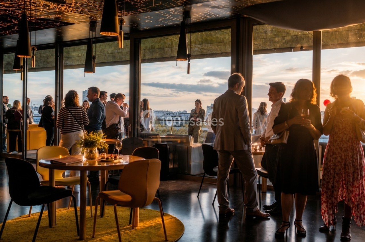 Groupe de personnes discutant dans un espace moderne avec vue panoramique sur la ville au coucher du soleil.