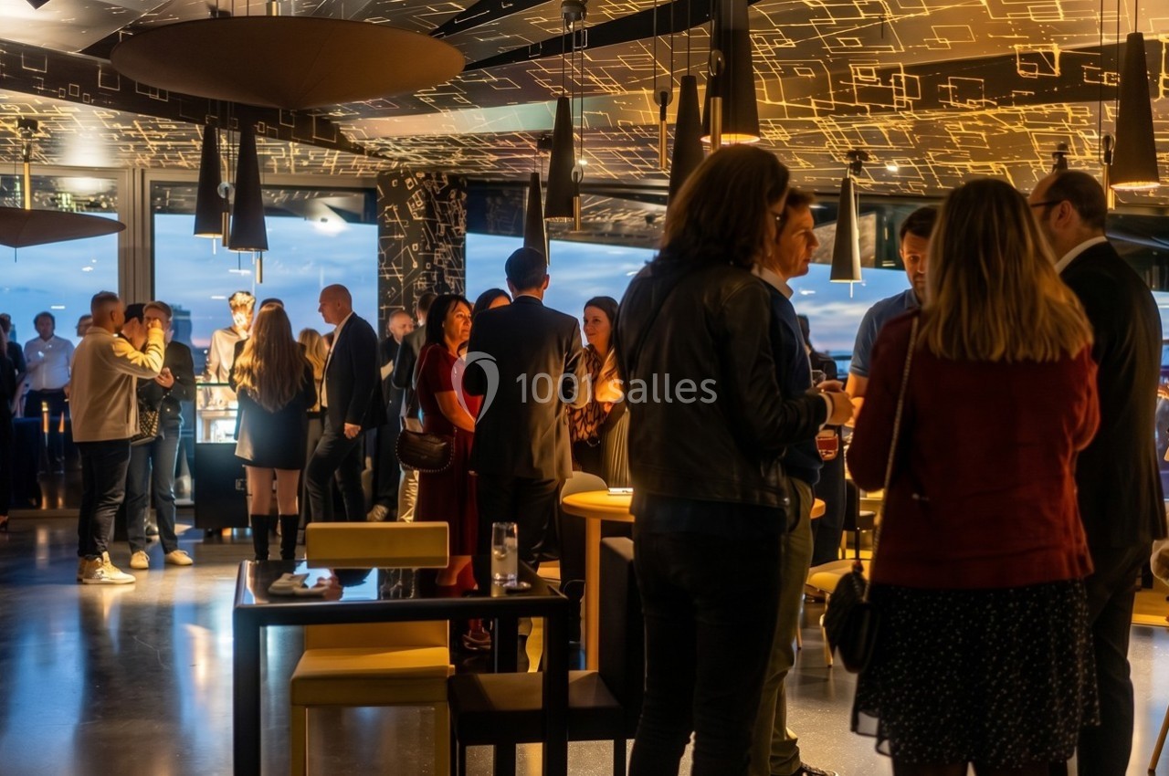 Personnes rassemblées dans un espace moderne et lumineux, discutant debout autour de tables hautes.