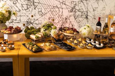 Un barman verse un liquide sombre d'une petite bouteille dans un verre à cocktail rempli d'une boisson mousseuse.